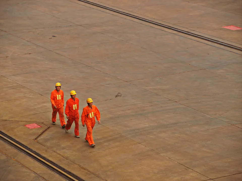 Tres trabajadores con casco y overol caminando en planta